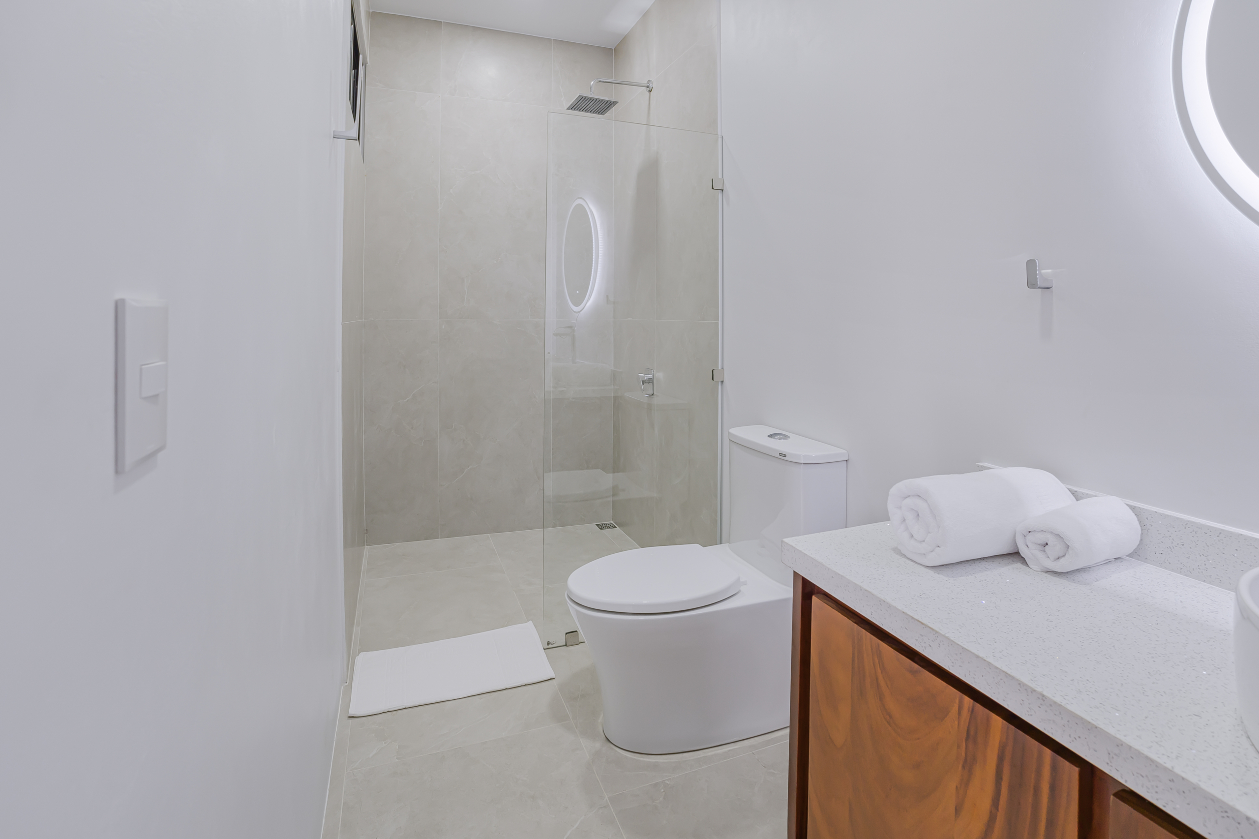 Bathroom with vessel sink, round mirror, shower, and toilet in La Fortuna, Costa Rica home