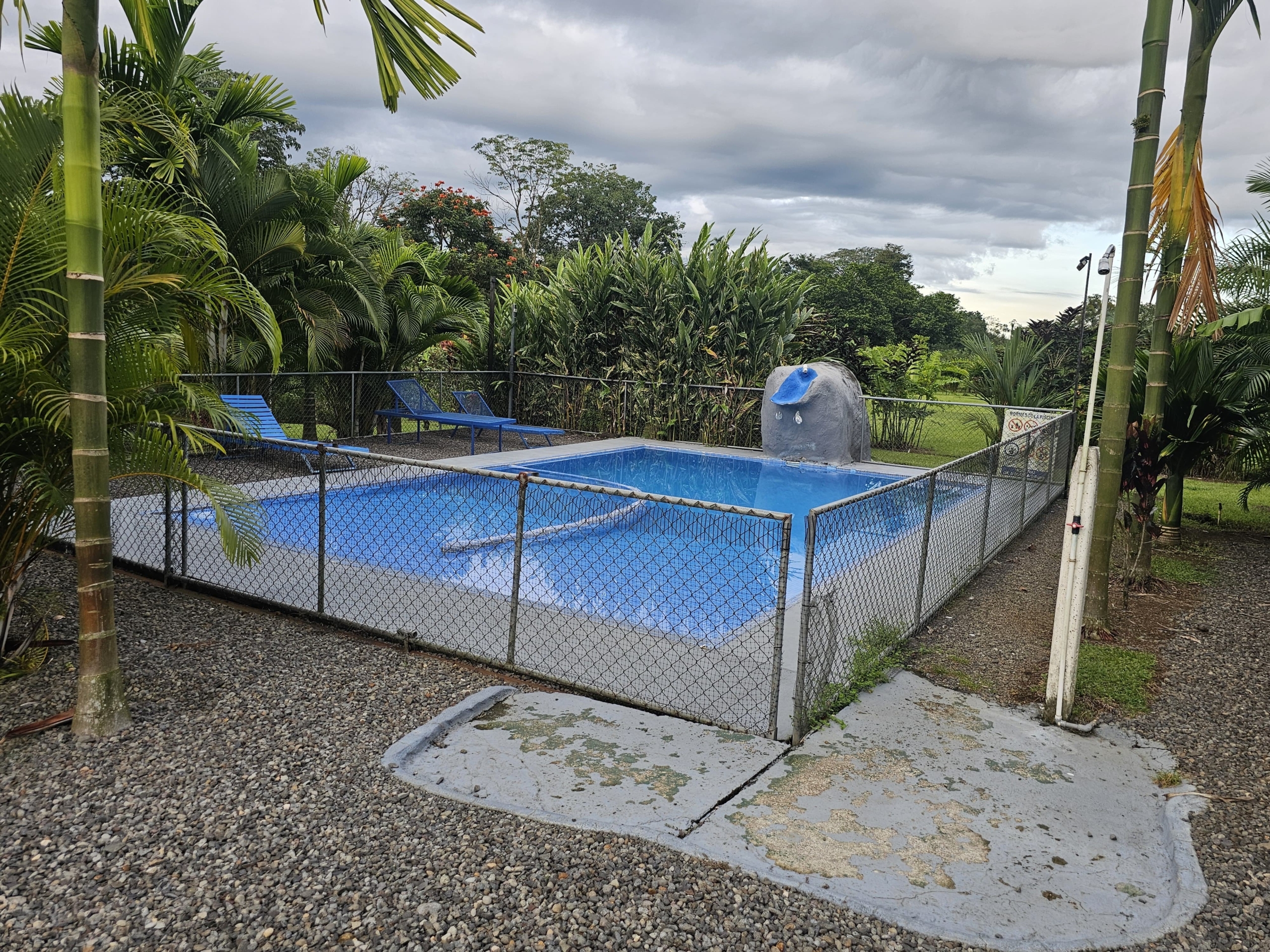 Fenced swimming pool with lounge chairs and stone fountain at the multi-home property near La Fortuna, Costa Rica